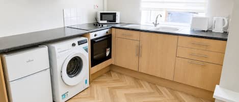 Une cuisine compacte équipée d’un lave-linge, d’un four à micro-ondes et d’un grille-pain.