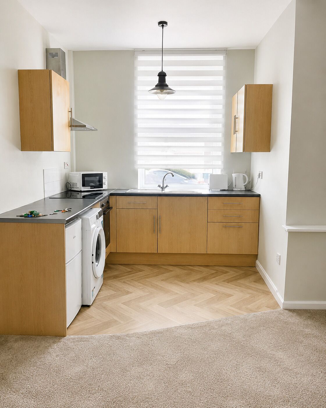 Una cocina compacta con lavadora, microondas y un lavabo con ventana arriba.