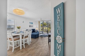 Ein modernes Wohnzimmer mit Essbereich, Deckenventilator und einem großen Fenster mit Vorhängen.