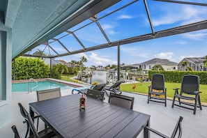 A covered patio with a pool, outdoor seating, and a view of a residential area. - Serene Waterfront Bliss – Private Pool Home Near Beach Access, Sleeps 8 (Marco Island)
