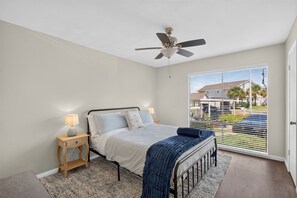 A bedroom with a bed, bedside tables, a ceiling fan, and a view of the outside. - Bombora, a Lake View Escape at April Sound. (Montgomery)