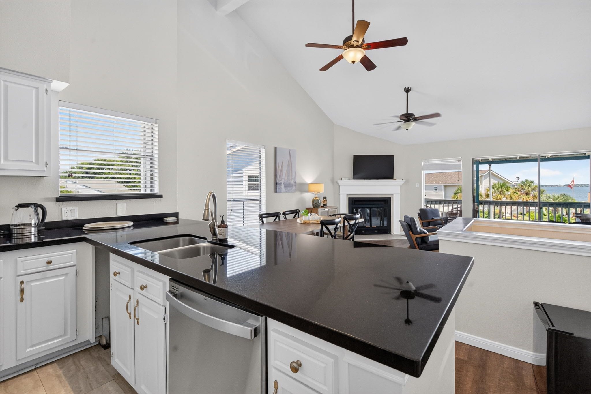 A spacious kitchen with a central island, white cabinetry, and a dining area with a view.