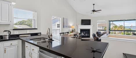 A spacious kitchen with a central island, white cabinetry, and a dining area with a view.