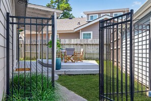A gated backyard with a wooden deck, a table and chairs, and a grassy area. - Bombora, a Lake View Escape at April Sound. (Montgomery)