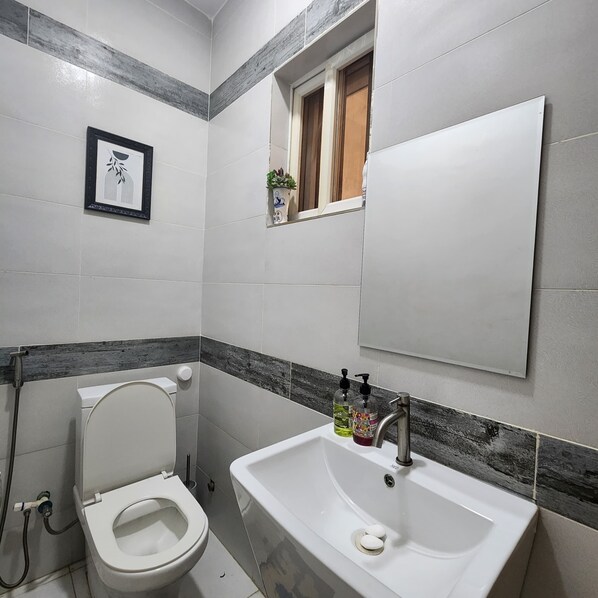 Ein Badezimmer mit Toilette, Waschbecken und einem gerahmten Bild an der Wand.