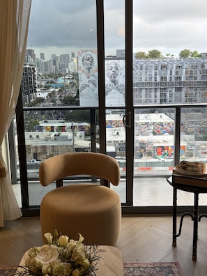 Une pièce dotée d’une grande fenêtre, d’une chaise, d’une petite table et d’un arrangement floral.