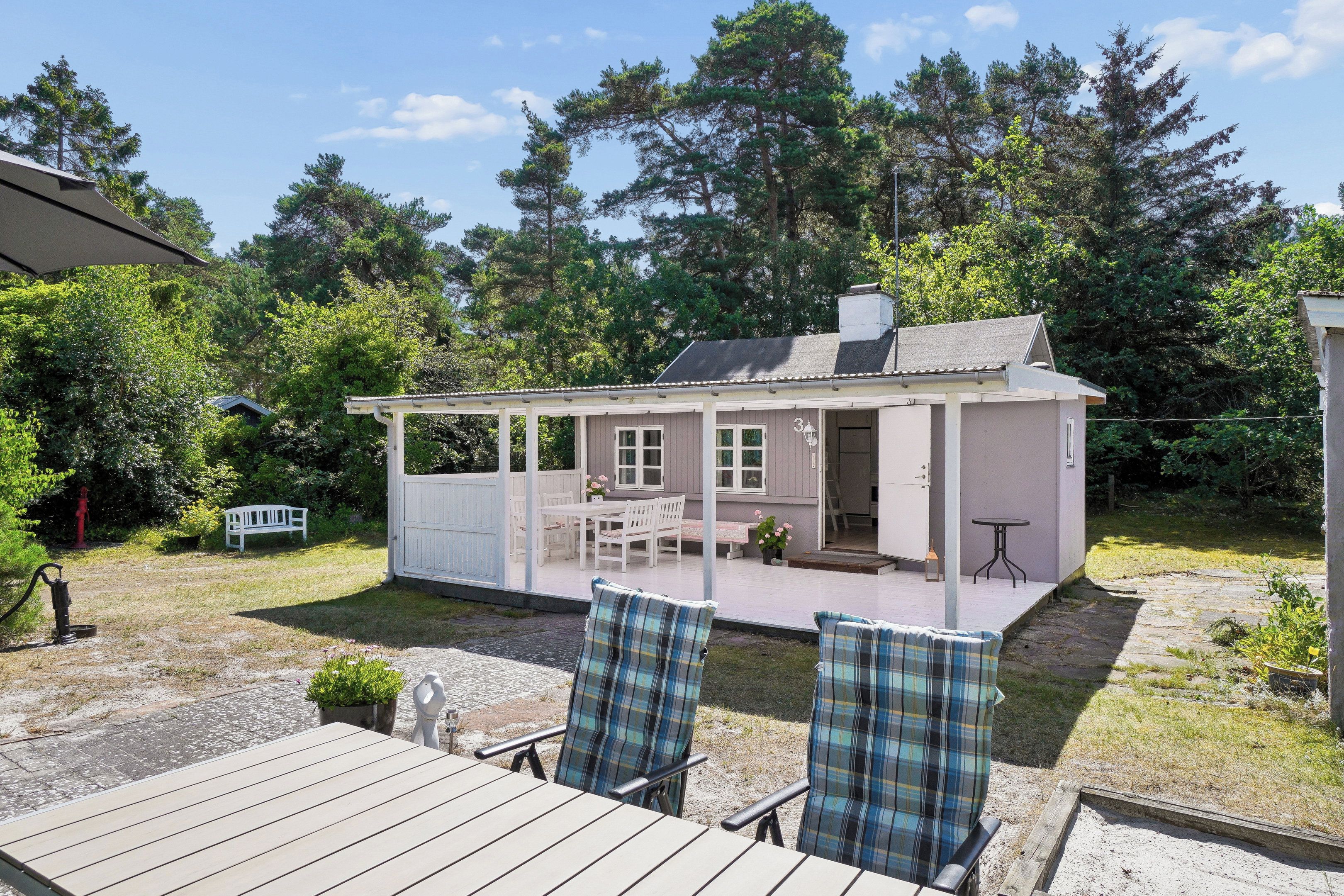 Une petite maison avec une véranda, une table et deux chaises.