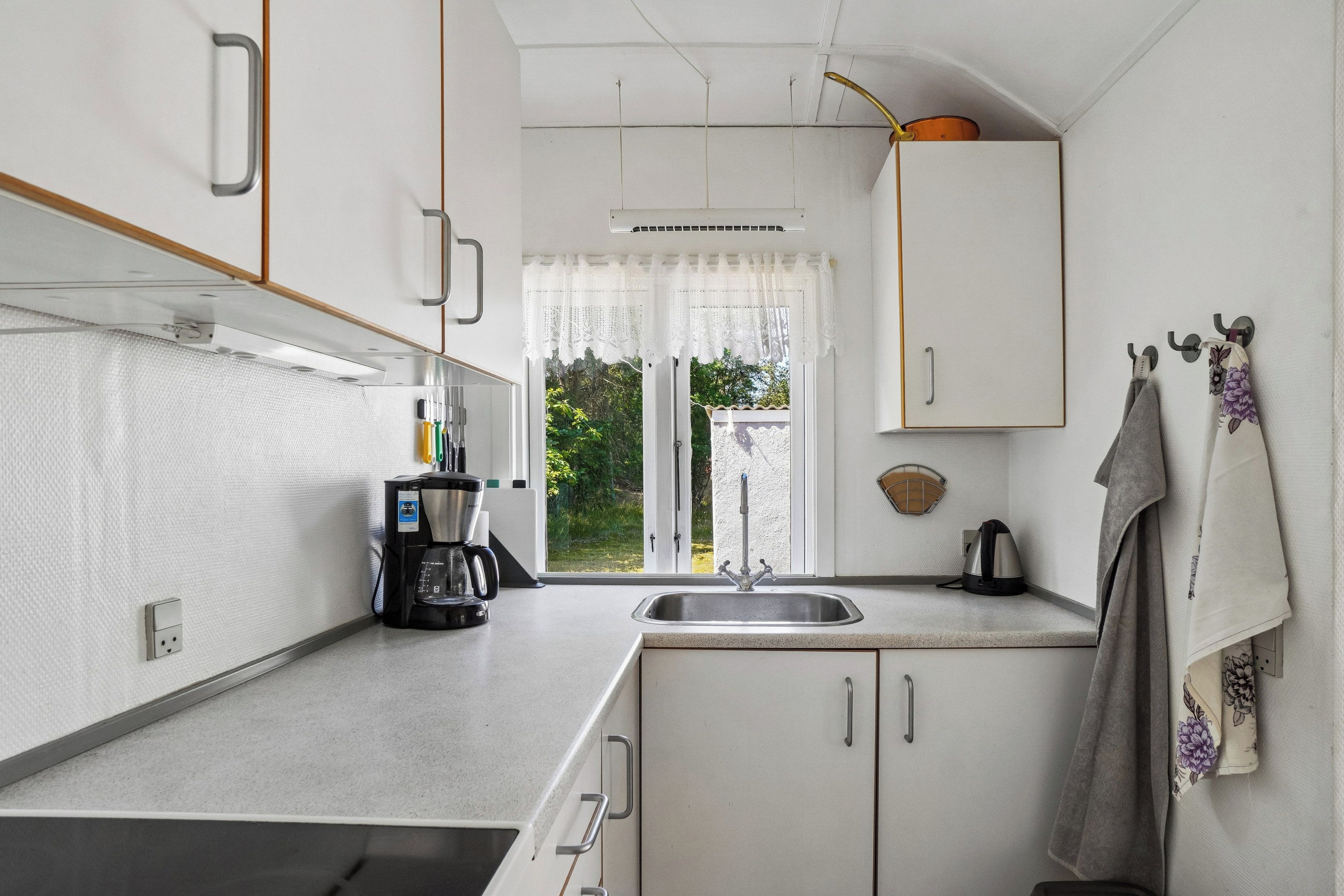 A compact kitchen with a built-in oven, a coffee maker, and a kettle.