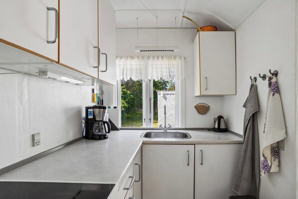 A compact kitchen with a built-in oven, a coffee maker, and a kettle.