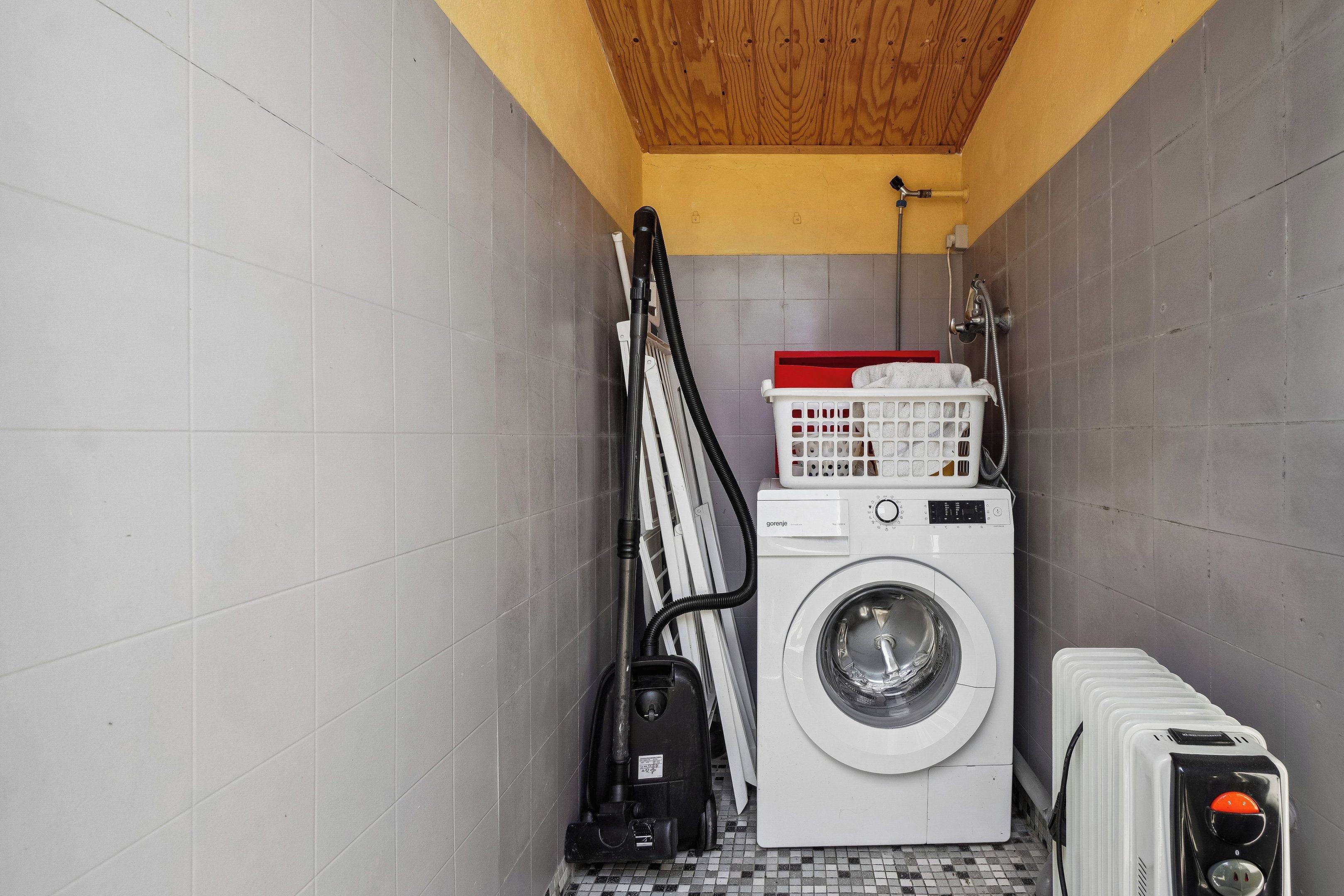 Une petite buanderie équipée d’un lave-linge, d’un sèche-linge et d’un étendoir à linge empilable.