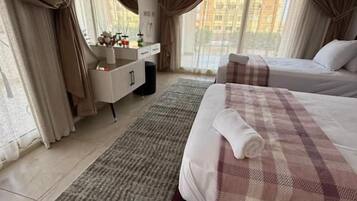 A hotel room with a bed, a bedside table, a mirror, a dresser, and a window with curtains.