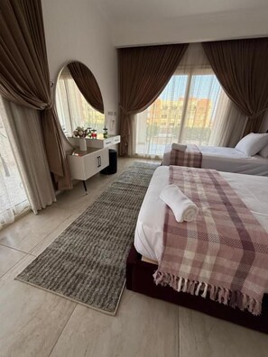 Une chambre d’hôtel avec un lit, une table de chevet, un miroir, une commode et une fenêtre avec des rideaux.