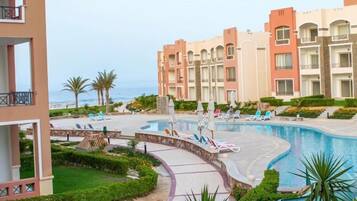 A resort with a swimming pool, lounge chairs, and a view of the sea.