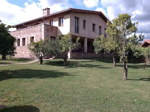 A two-story house with a stone facade, a flat roof, and a front porch. - Casa Rural La Flor del Naranjo (Cadalso)