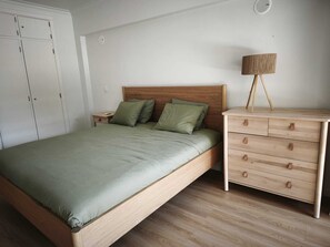 A bedroom with a bed, a nightstand, a dresser, and a lamp. - Atlantic Ocean Flat | Stunning Ocean View in Cascais (Cascais)