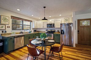 A modern kitchen with a dining area, stainless steel appliances, and a wooden floor. - Locklyn's Loft Views, Hot Tub, Game Room & MORE! (Gatlinburg)