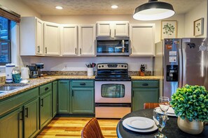 A kitchen with white cabinets, a stainless steel refrigerator, a microwave, and a stove. - Locklyn's Loft Views, Hot Tub, Game Room & MORE! (Gatlinburg)