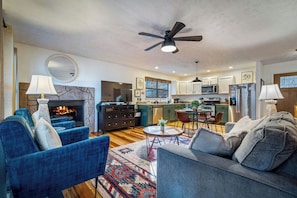 A living room with a fireplace, blue sofas, a coffee table, and a ceiling fan. - Locklyn's Loft Views, Hot Tub, Game Room & MORE! (Gatlinburg)