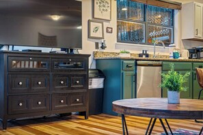A kitchen with a wooden floor, a dark-colored cabinet, a dishwasher, and a window with a view. - Locklyn's Loft Views, Hot Tub, Game Room & MORE! (Gatlinburg)