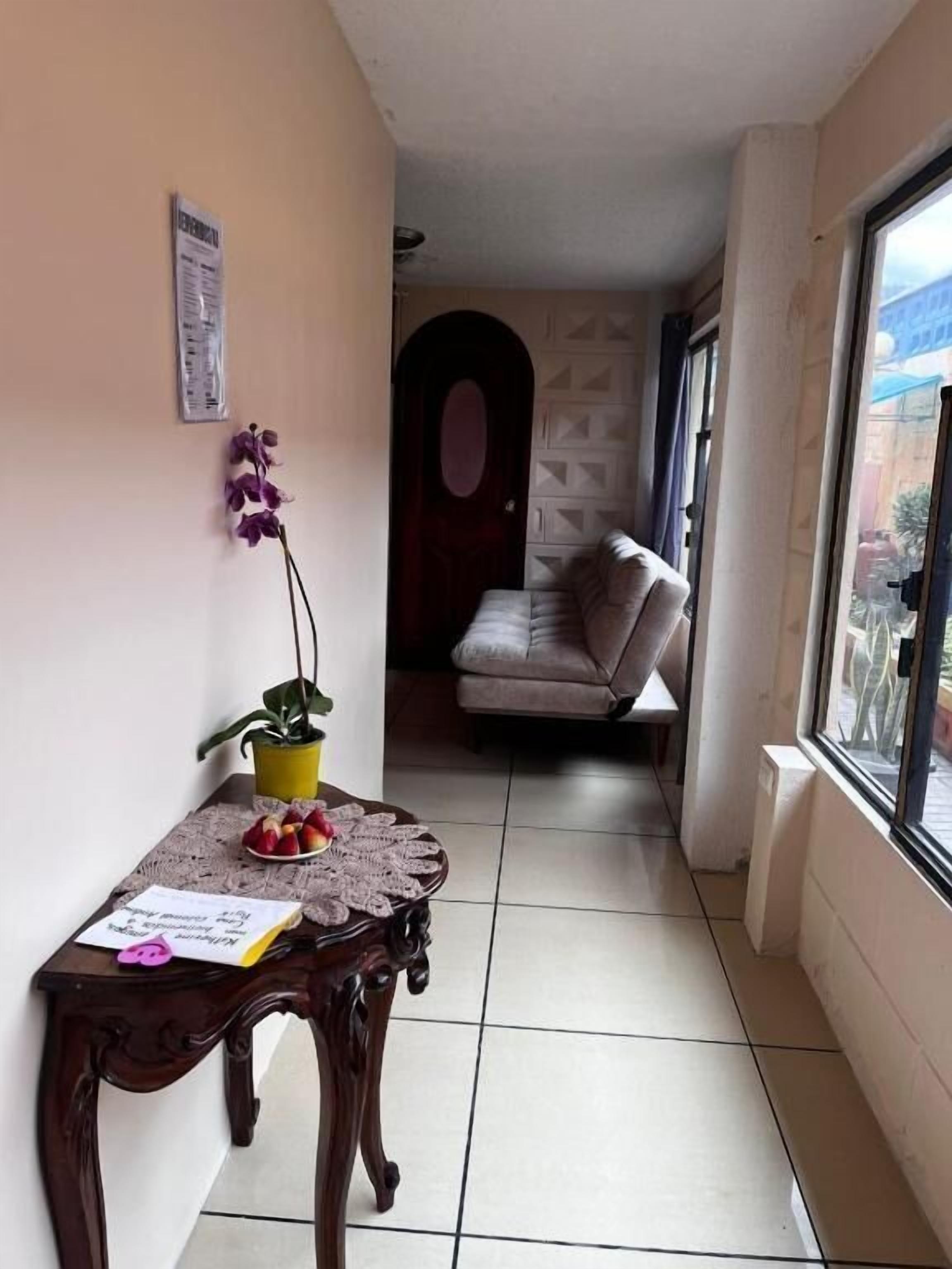 Un pasillo con una mesa de madera, una planta en maceta y un banco.