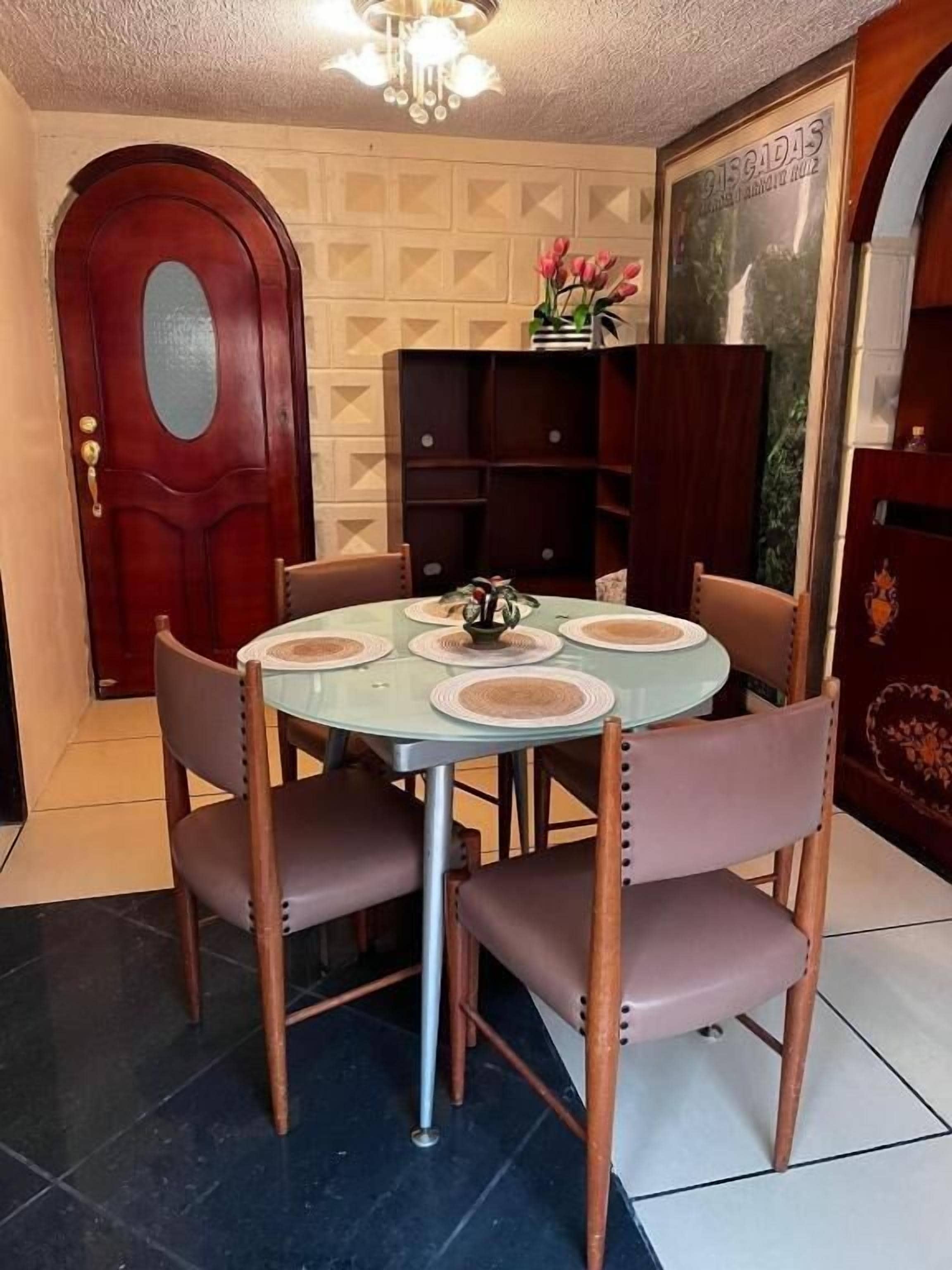 Un coin repas avec une table ronde, quatre chaises et un lustre.
