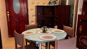Un coin repas avec une table ronde, quatre chaises et un lustre.
