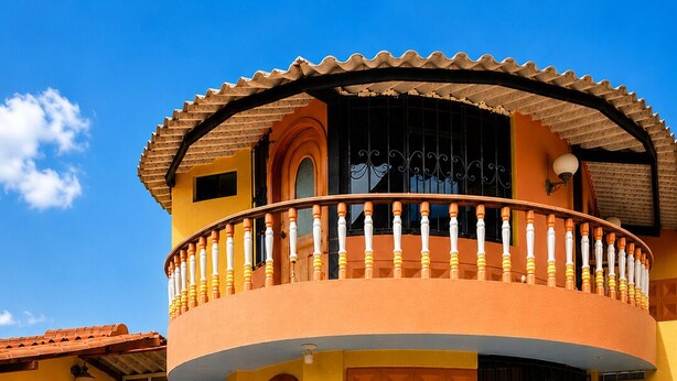 Un edificio de dos plantas con un balcón, un ventanal grande y una puerta.