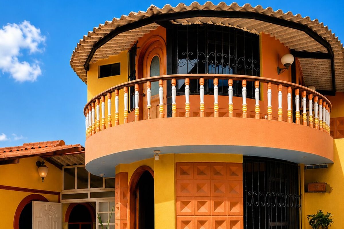 A two-story building with a balcony, a large window, and a door.