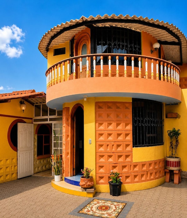 A two-story building with a balcony, a large window, and a door. - Casa Andina Pujilí (Pujilí)