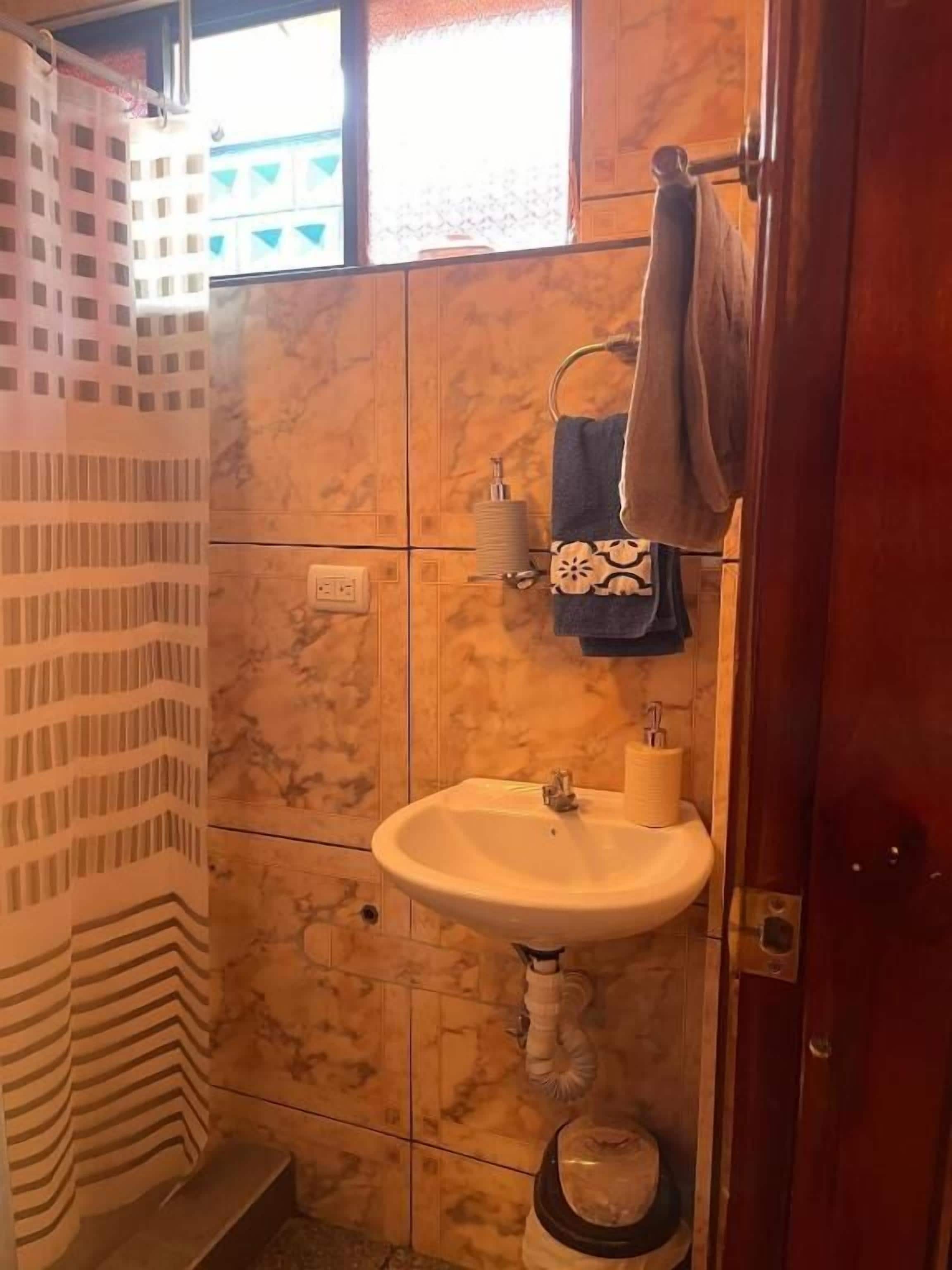 A bathroom with a marble wall, a sink, and a towel rack.