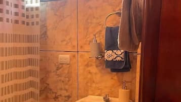 A bathroom with a marble wall, a sink, and a towel rack.
