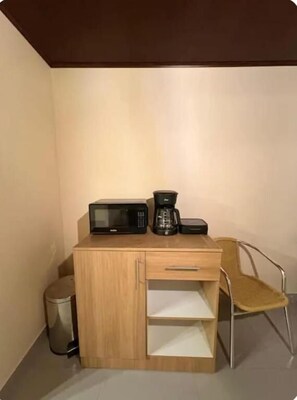 A small kitchenette with a microwave, coffee maker, and a chair. - Casa Andina Pujilí (Pujilí)