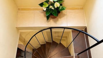 Un escalier en colimaçon avec une rampe et un pot de fleurs placé au-dessus.