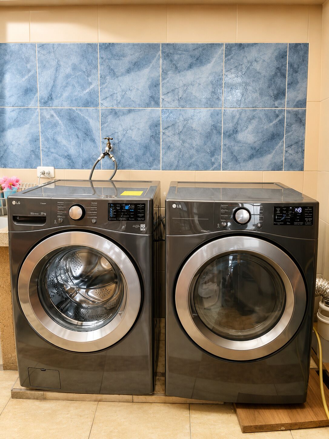 Dos lavadoras LG de carga frontal en un cuarto de lavado con azulejos de mármol azul en la pared.