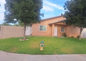 A residential house with a front lawn, a fire hydrant, and a gated driveway.