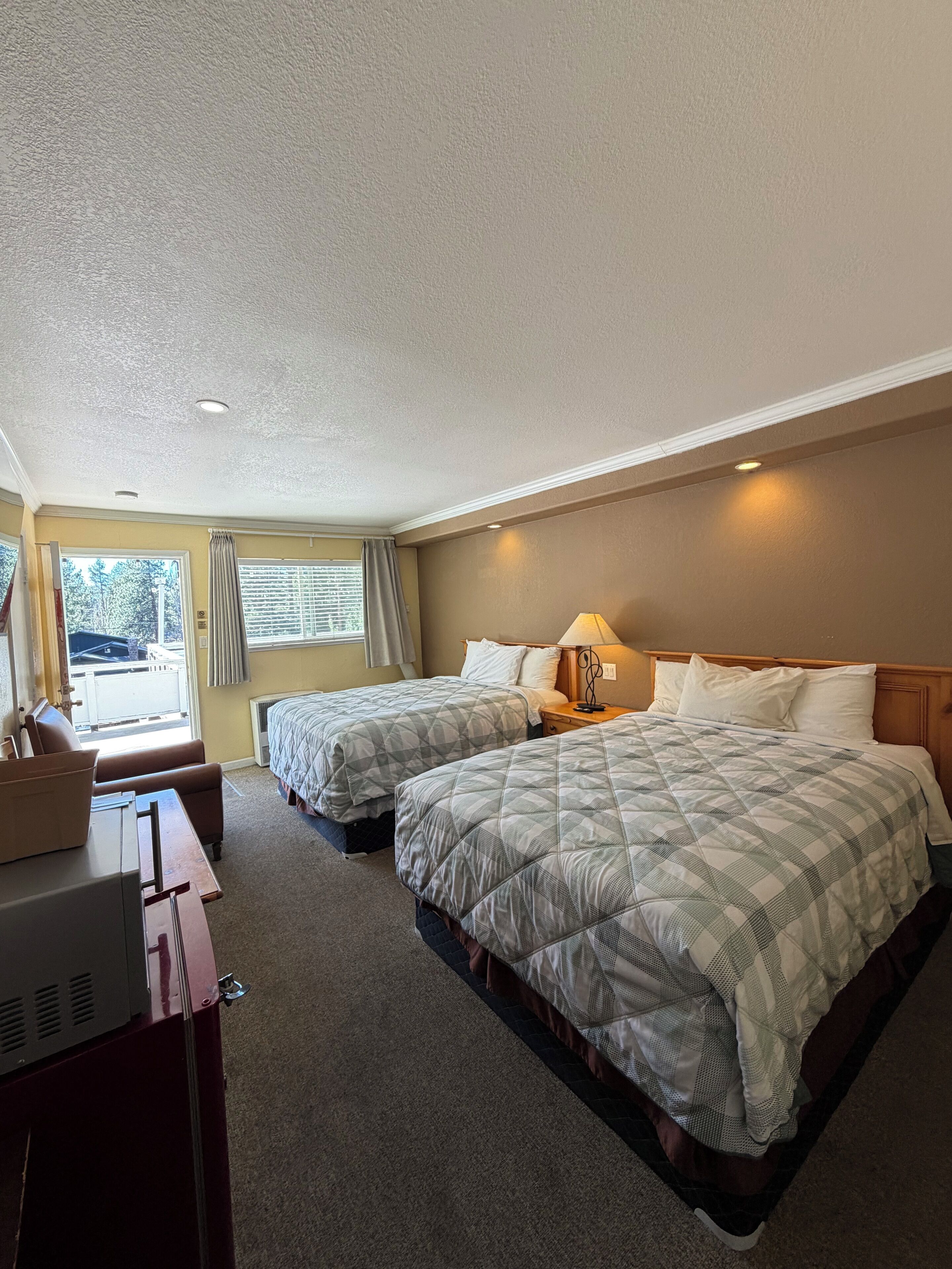 Une chambre d’hôtel avec deux lits, un bureau et une vue sur l’extérieur.