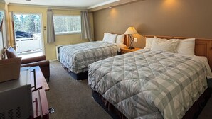 Una camera d'albergo con due letti, una scrivania e vista sull'esterno.