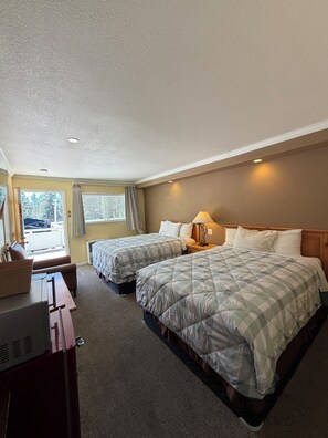 Quarto de hotel com duas camas, uma escrivaninha e vista para o exterior.