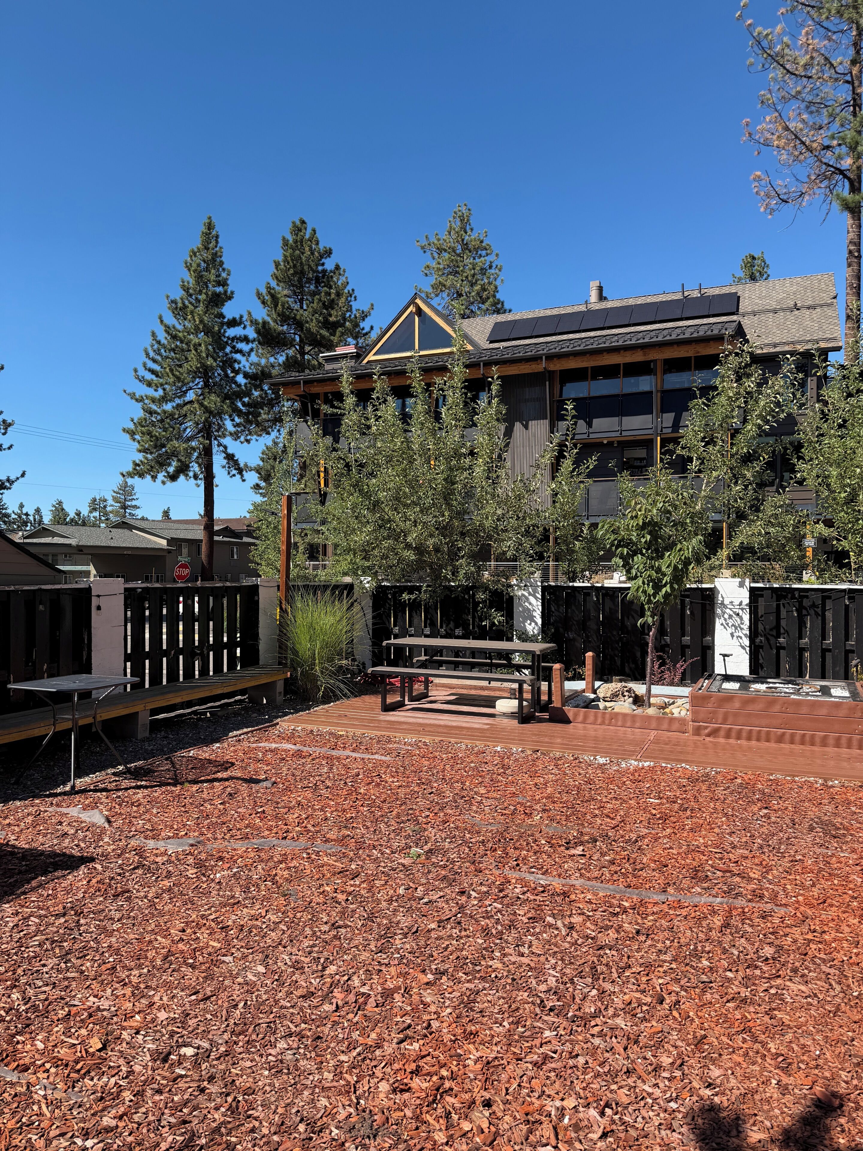 Un edificio de diseño moderno, con una terraza de madera y una mesa de picnic.