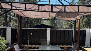Un patio esterno con zona salotto coperta, un tavolo e sedie.