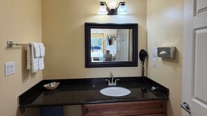 Un bagno con lavandino, mobile contenitore, specchio, portasciugamani e lampada.