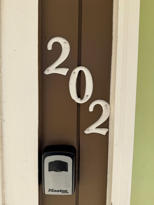 Uma porta com os números '202' e um interfone identificado como 'Master Lock'.
