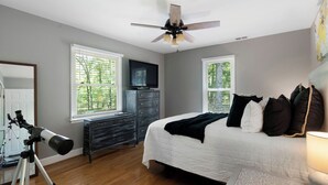 Ein Schlafzimmer mit einem Bett, einem Schminktisch, einem Deckenventilator und einem Teleskop.