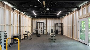 Ein Fitnessstudio mit verschiedenen Trainingsgeräten, darunter Kurzhanteln, Bänke und Kraftstationen.