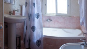 Un bagno con lavandino, doccia e finestra.