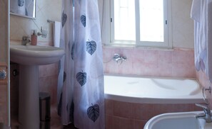 Ein Badezimmer mit Waschbecken, Dusche und Fenster.