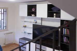 Ein Zimmer mit Treppe, Heizkörper, Fenster und Bücherregal.