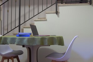 Ein Tisch mit einem Laptop, Büchern und einem roten Gegenstand, vermutlich einem Notizbuch, auf einer grünen Tischdecke.