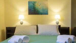 Una camera d'albergo con un letto, due cuscini, due lampade da comodino e un quadro appeso al muro.
