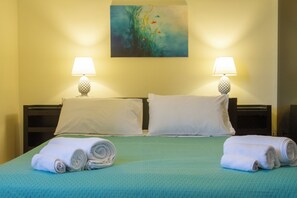 Ein Hotelzimmer mit einem Bett, zwei Kissen, zwei Nachttischlampen und einem Gemälde an der Wand.